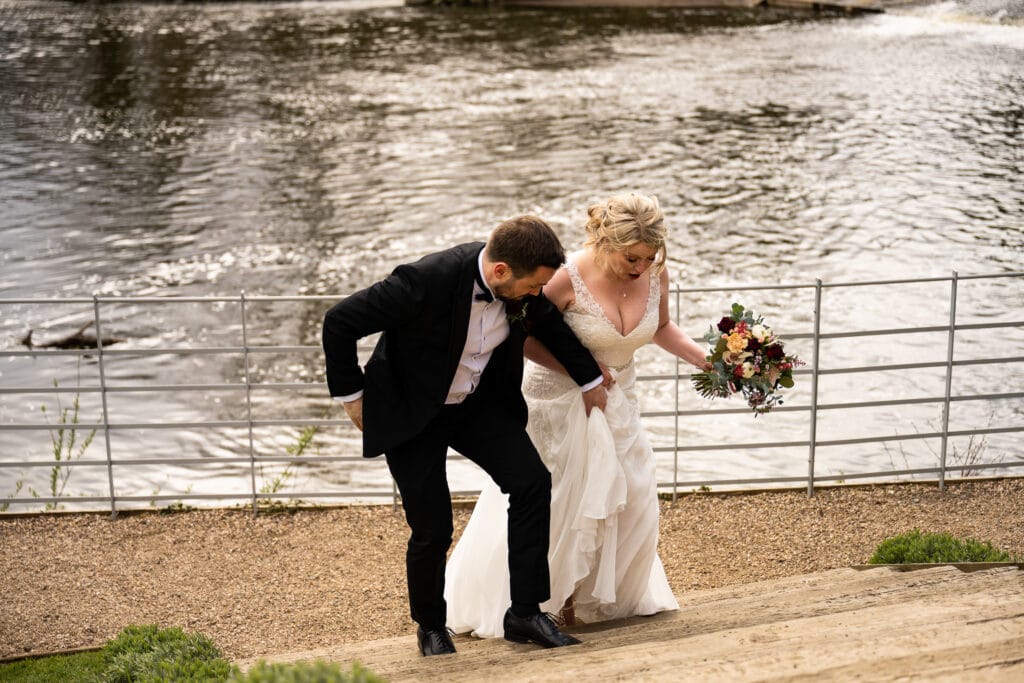 Groom helps bride with her dress on steps