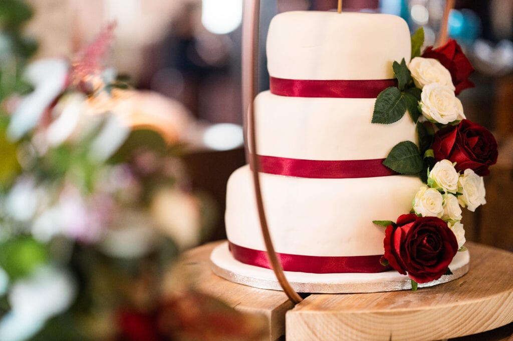Tiered wedding cake with red ribbon and flowers
